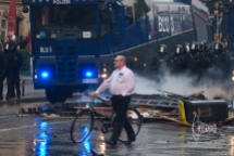 Man walking through riot with his bike