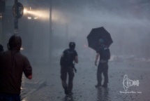 Man standing in umbrella charching water cannon