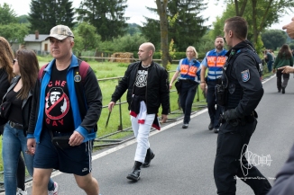 Participant on the way to the festival area with swastika shirt - about to get arrested by police.
